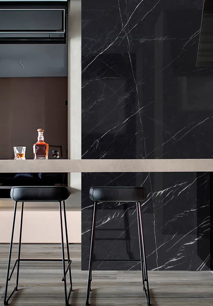 Modern kitchen with black marble wall and bar stools.
