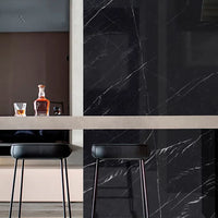 Modern kitchen with black marble wall and bar stools.