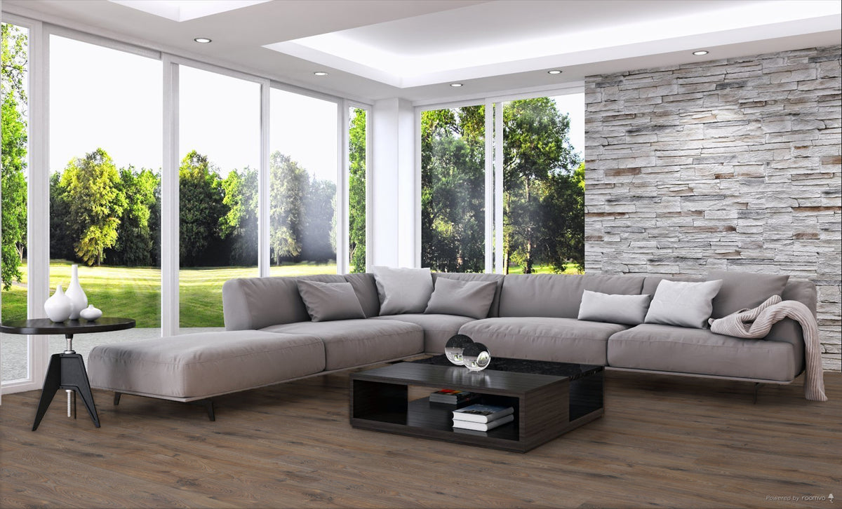 A modern light gray sectional sofa with matching throw pillows arranged in an L-shape in a bright living room with large windows, a wood-paneled accent wall, and a black coffee table.