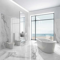 Modern bathroom with marble walls and floor, freestanding bathtub, and ocean view.