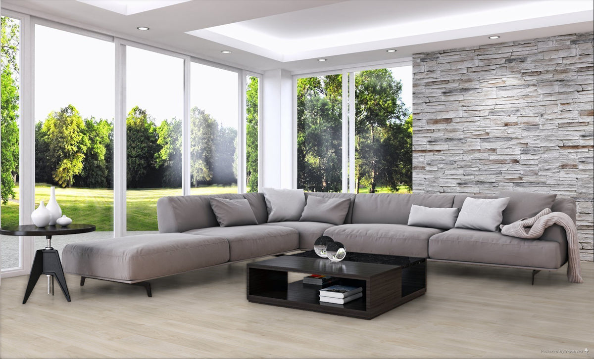 A modern L-shaped sectional sofa in light gray fabric, styled in a contemporary living room with a black coffee table, a side table, a stone accent wall, and large windows overlooking a green lawn.